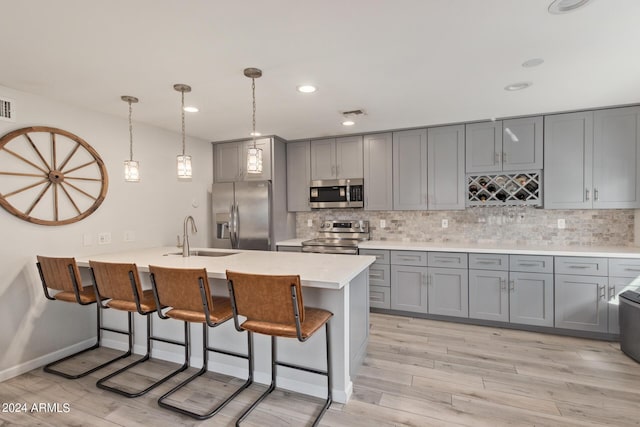 kitchen with sink, a breakfast bar area, tasteful backsplash, hanging light fixtures, and appliances with stainless steel finishes