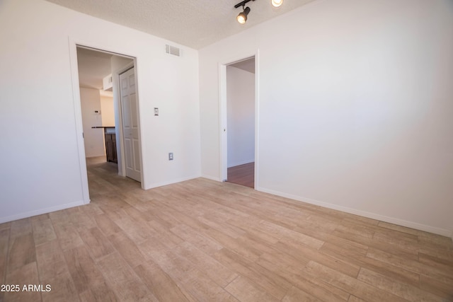 empty room with light hardwood / wood-style floors and a textured ceiling