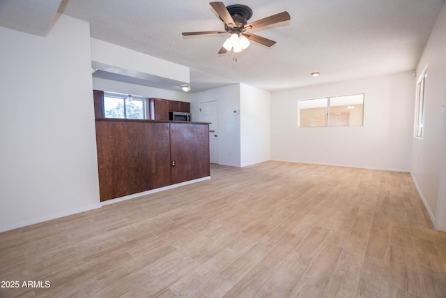 unfurnished living room with a textured ceiling, ceiling fan, and light hardwood / wood-style floors