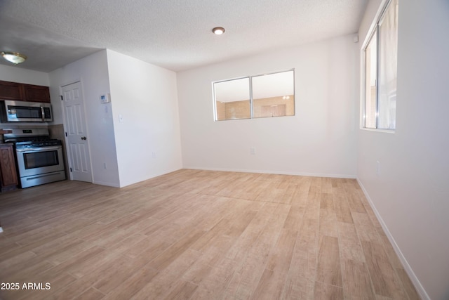 unfurnished living room with a textured ceiling and light hardwood / wood-style floors