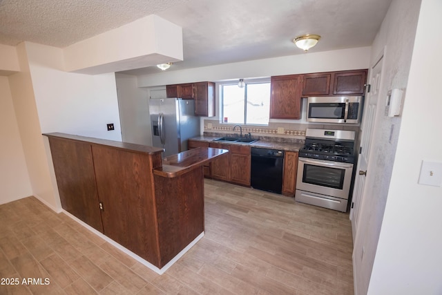 kitchen featuring sink, stainless steel appliances, light wood-type flooring, and kitchen peninsula