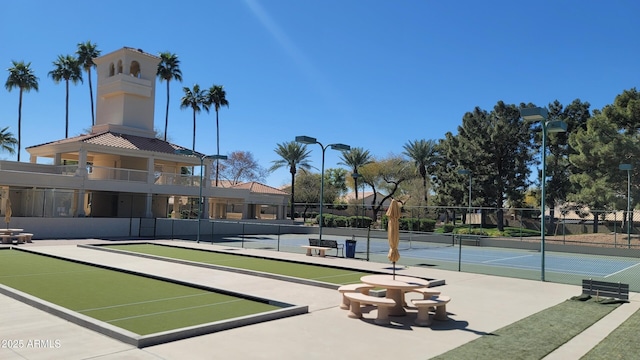 view of community with a tennis court and fence