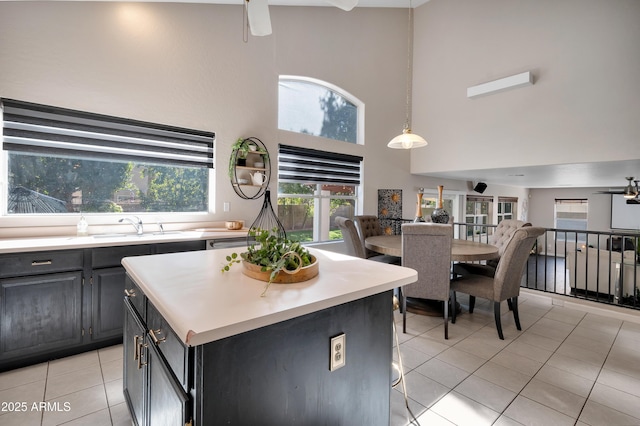 kitchen with a center island, light countertops, open floor plan, light tile patterned flooring, and a sink