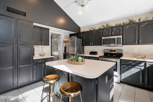 kitchen with lofted ceiling, light tile patterned floors, stainless steel appliances, and light countertops