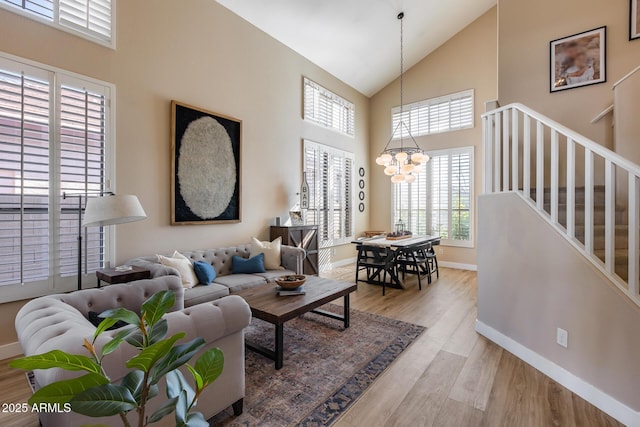 living room with an inviting chandelier, light hardwood / wood-style flooring, and high vaulted ceiling