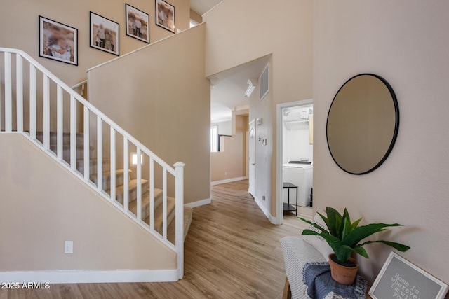 interior space featuring hardwood / wood-style flooring, a towering ceiling, and washer / clothes dryer