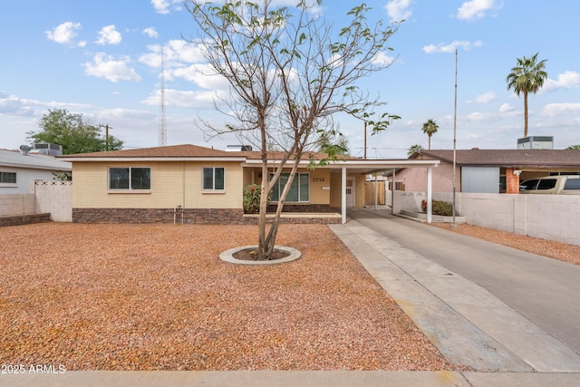 ranch-style house featuring concrete driveway, an attached carport, and fence