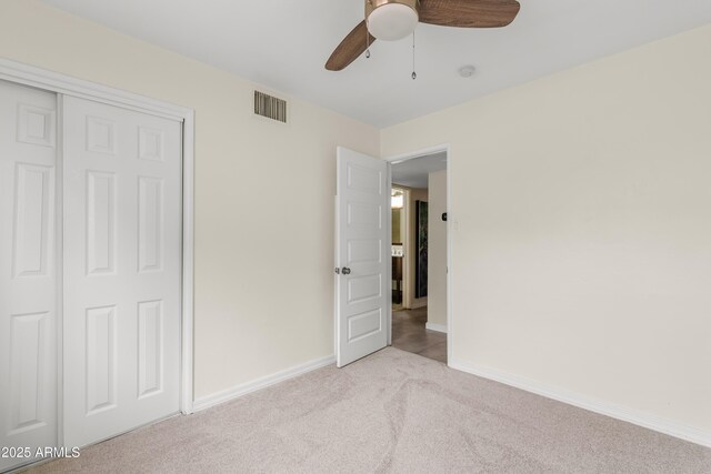 unfurnished bedroom featuring a closet, visible vents, carpet flooring, ceiling fan, and baseboards