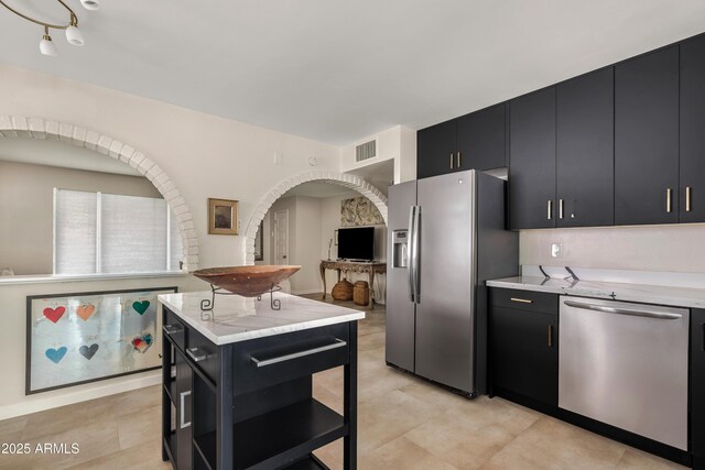 kitchen featuring dark cabinets, visible vents, appliances with stainless steel finishes, a center island, and open shelves