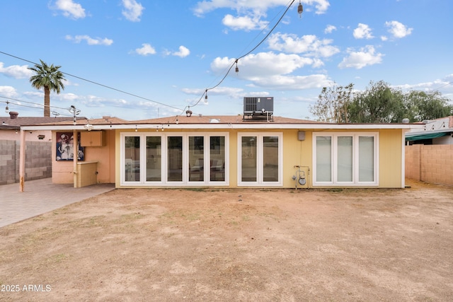 rear view of house featuring fence, cooling unit, and a patio