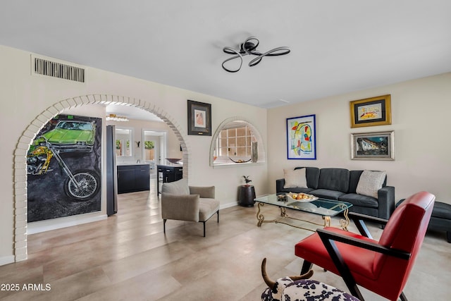 interior space featuring arched walkways, a ceiling fan, visible vents, and baseboards