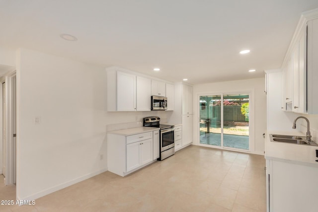 kitchen with a sink, light countertops, stainless steel appliances, and white cabinetry