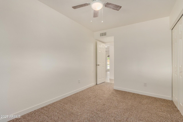 spare room with light colored carpet, baseboards, visible vents, and ceiling fan