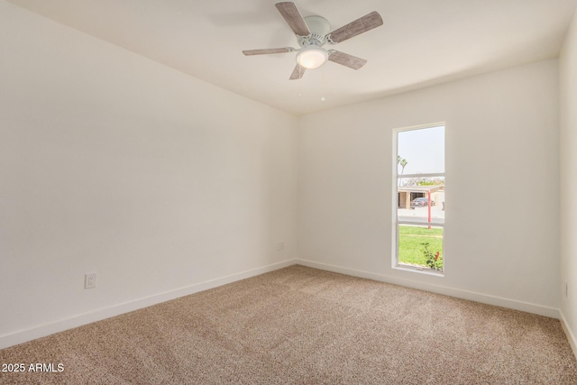 carpeted spare room featuring baseboards and ceiling fan