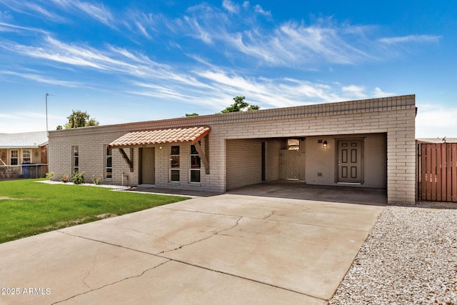 view of front of home featuring fence, driveway, a front lawn, and brick siding