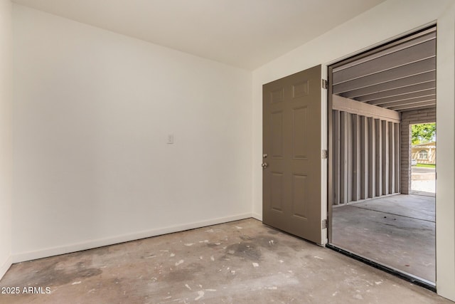 spare room featuring baseboards and concrete floors