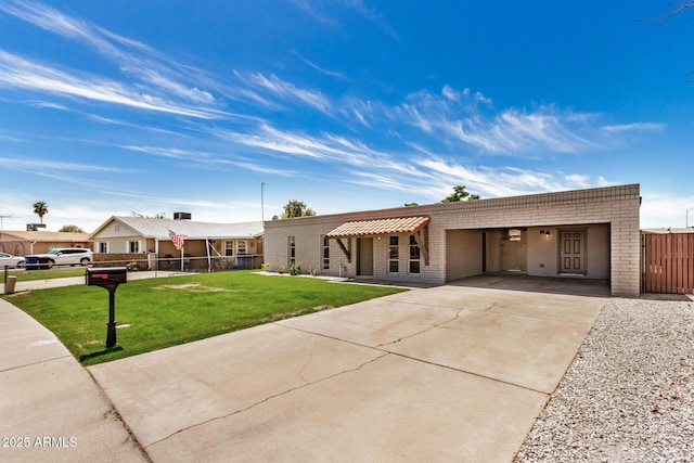 single story home featuring fence, a front lawn, brick siding, an attached carport, and driveway