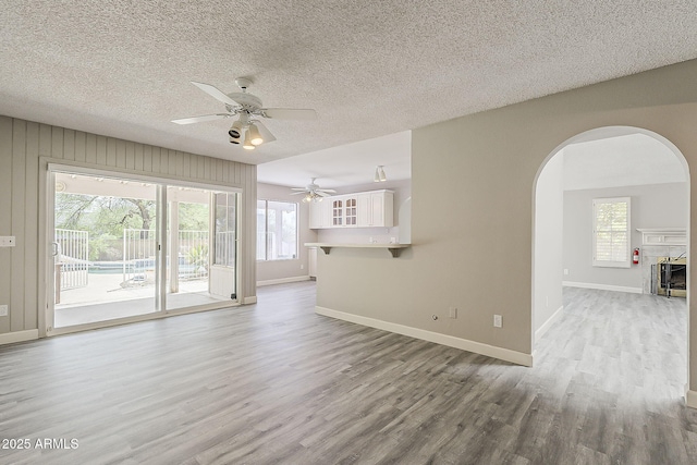 4627 E Mcneil St, Phoenix, AZ 85044 - unfurnished living room featuring ceiling fan, wood finished floors, arched walkways, baseboards, and a textured ceiling