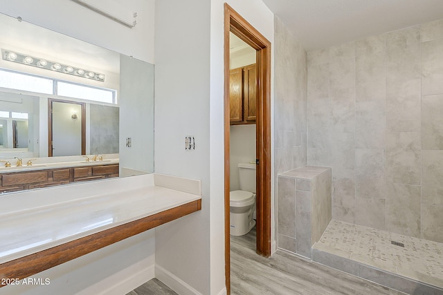 4627 E Mcneil St, Phoenix, AZ 85044 - bathroom featuring wood finished floors, toilet, baseboards, vanity, and tiled shower