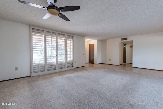 unfurnished room with a textured ceiling, light colored carpet, and ceiling fan