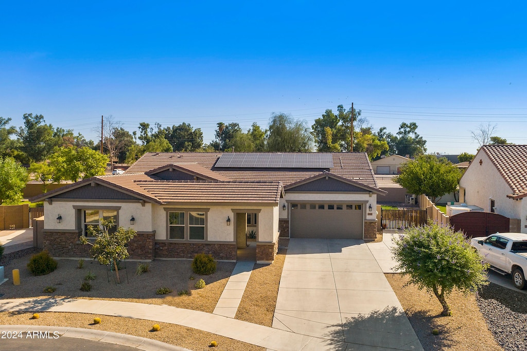 single story home featuring solar panels and a garage