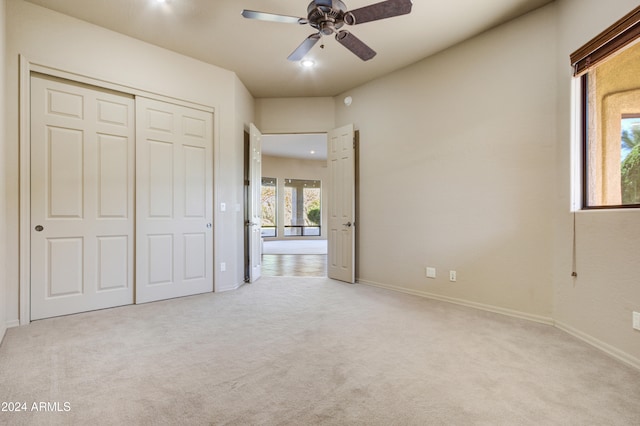 unfurnished bedroom featuring light carpet, a closet, and ceiling fan