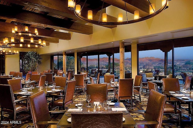 dining area featuring beam ceiling, a mountain view, a high ceiling, and an inviting chandelier