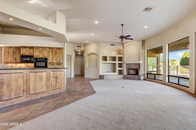 kitchen with dark stone countertops, light carpet, a fireplace, and black appliances