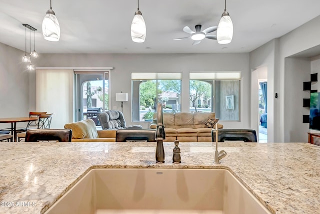 16426 W Piccadilly Rd, Goodyear, AZ 85395 - kitchen featuring healthy amount of natural light, open floor plan, ceiling fan, and light stone counters