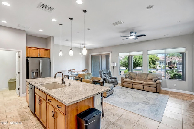 16426 W Piccadilly Rd, Goodyear, AZ 85395 - kitchen with stainless steel appliances, ceiling fan, light stone counters, a center island with sink, and hanging light fixtures
