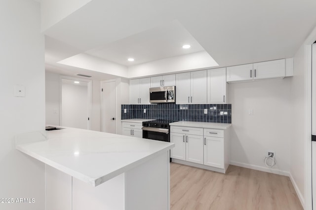 kitchen featuring kitchen peninsula, black range with electric cooktop, white cabinetry, and light hardwood / wood-style floors