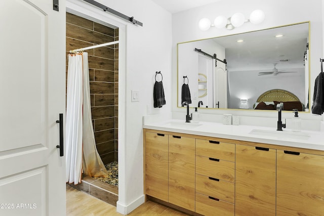 full bathroom featuring wood finished floors, a sink, a stall shower, and ceiling fan