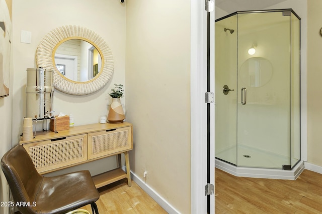 bathroom featuring a stall shower, baseboards, and wood finished floors