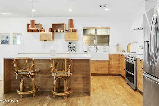 kitchen featuring visible vents, appliances with stainless steel finishes, light brown cabinets, a sink, and light wood-type flooring
