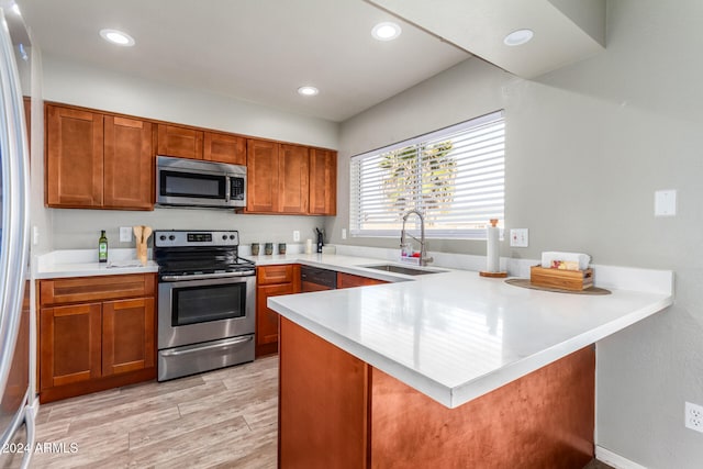 kitchen featuring sink, kitchen peninsula, stainless steel appliances, and light hardwood / wood-style flooring