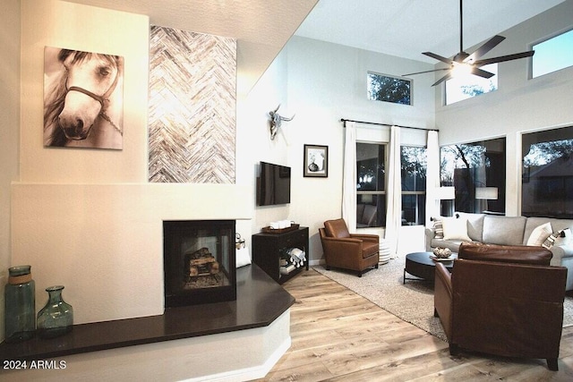 living room featuring a high ceiling, light wood-type flooring, and ceiling fan