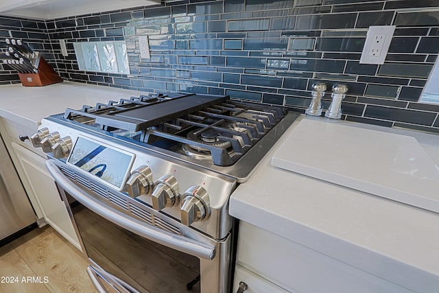 details featuring high end stove, light wood-type flooring, and backsplash