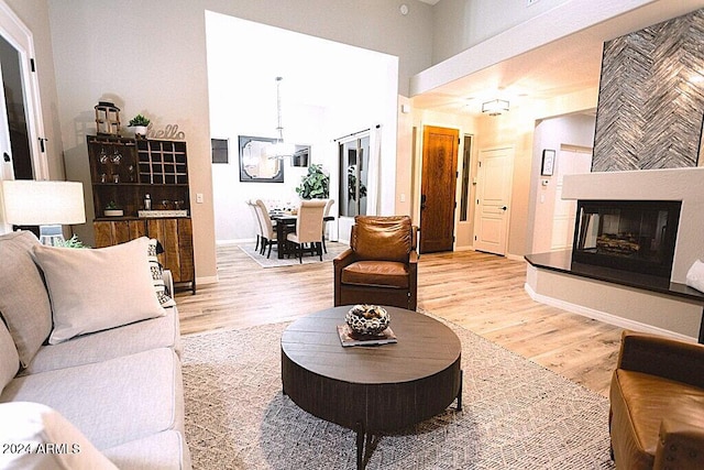 living room featuring a fireplace, a high ceiling, and light wood-type flooring