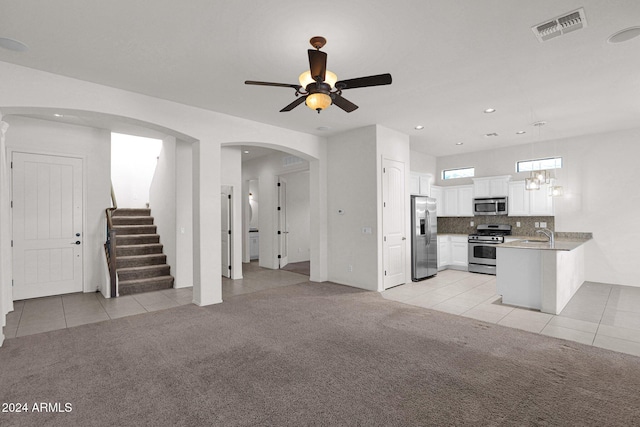 unfurnished living room featuring arched walkways, visible vents, light carpet, light tile patterned flooring, and stairs