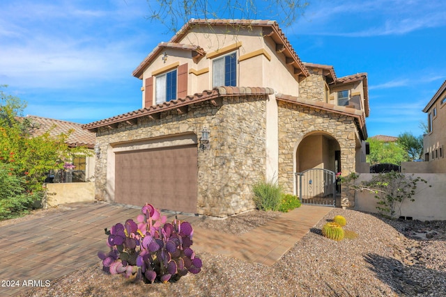 view of front of house with a garage, stone siding, a tile roof, and stucco siding