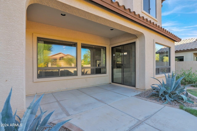 doorway to property featuring a patio area, a tile roof, and stucco siding