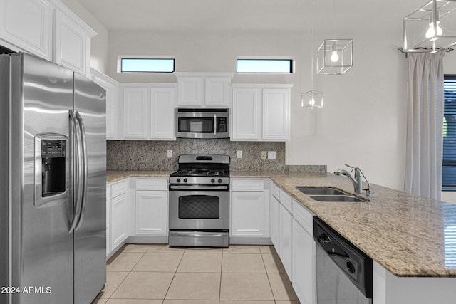 kitchen with appliances with stainless steel finishes, a sink, decorative light fixtures, and white cabinetry