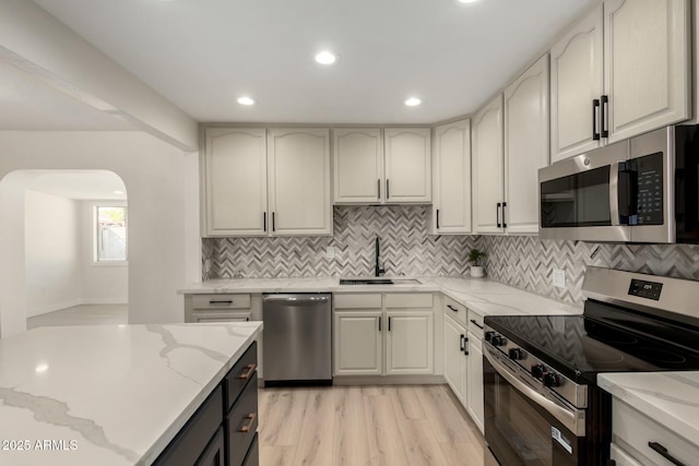 2240 W Cheery Lynn Rd, Phoenix, AZ 85015 - kitchen featuring arched walkways, a sink, appliances with stainless steel finishes, light stone countertops, and backsplash