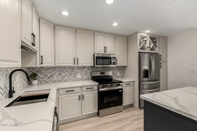 2240 W Cheery Lynn Rd, Phoenix, AZ 85015 - kitchen featuring light stone counters, decorative backsplash, stainless steel appliances, light wood finished floors, and a sink