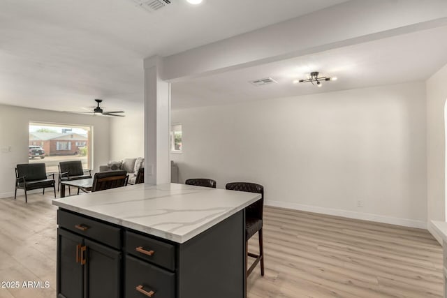 2240 W Cheery Lynn Rd, Phoenix, AZ 85015 - kitchen featuring open floor plan, a ceiling fan, visible vents, a breakfast bar area, and light wood finished floors