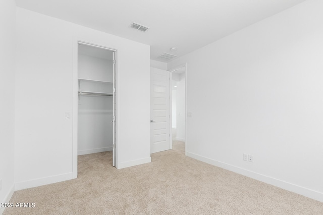 unfurnished bedroom with light colored carpet, a spacious closet, and a closet