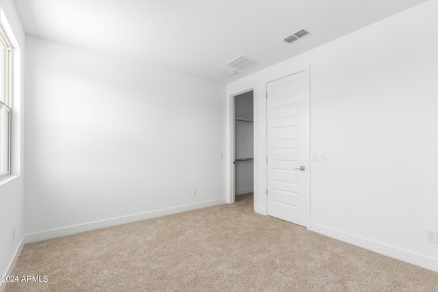 unfurnished bedroom with light carpet and a closet