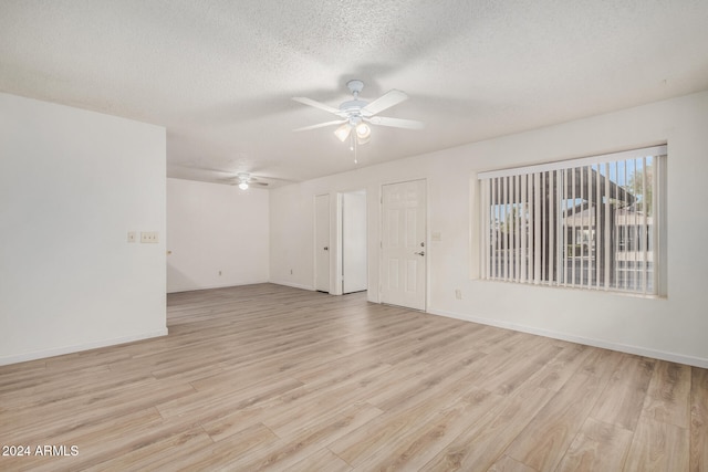 unfurnished room with ceiling fan, light wood-type flooring, and a textured ceiling