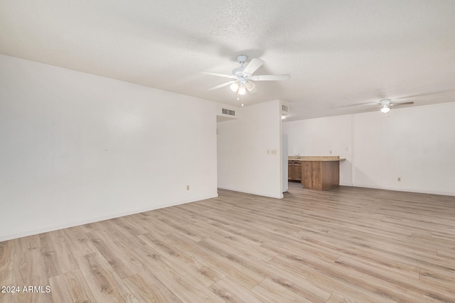 spare room with a textured ceiling, light wood-type flooring, and ceiling fan