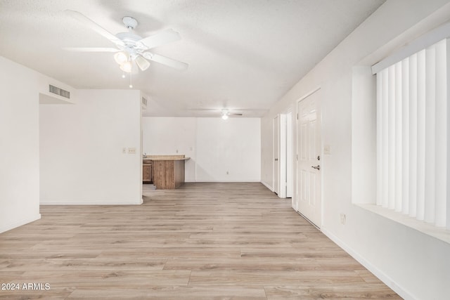 unfurnished room with ceiling fan, a textured ceiling, and light wood-type flooring